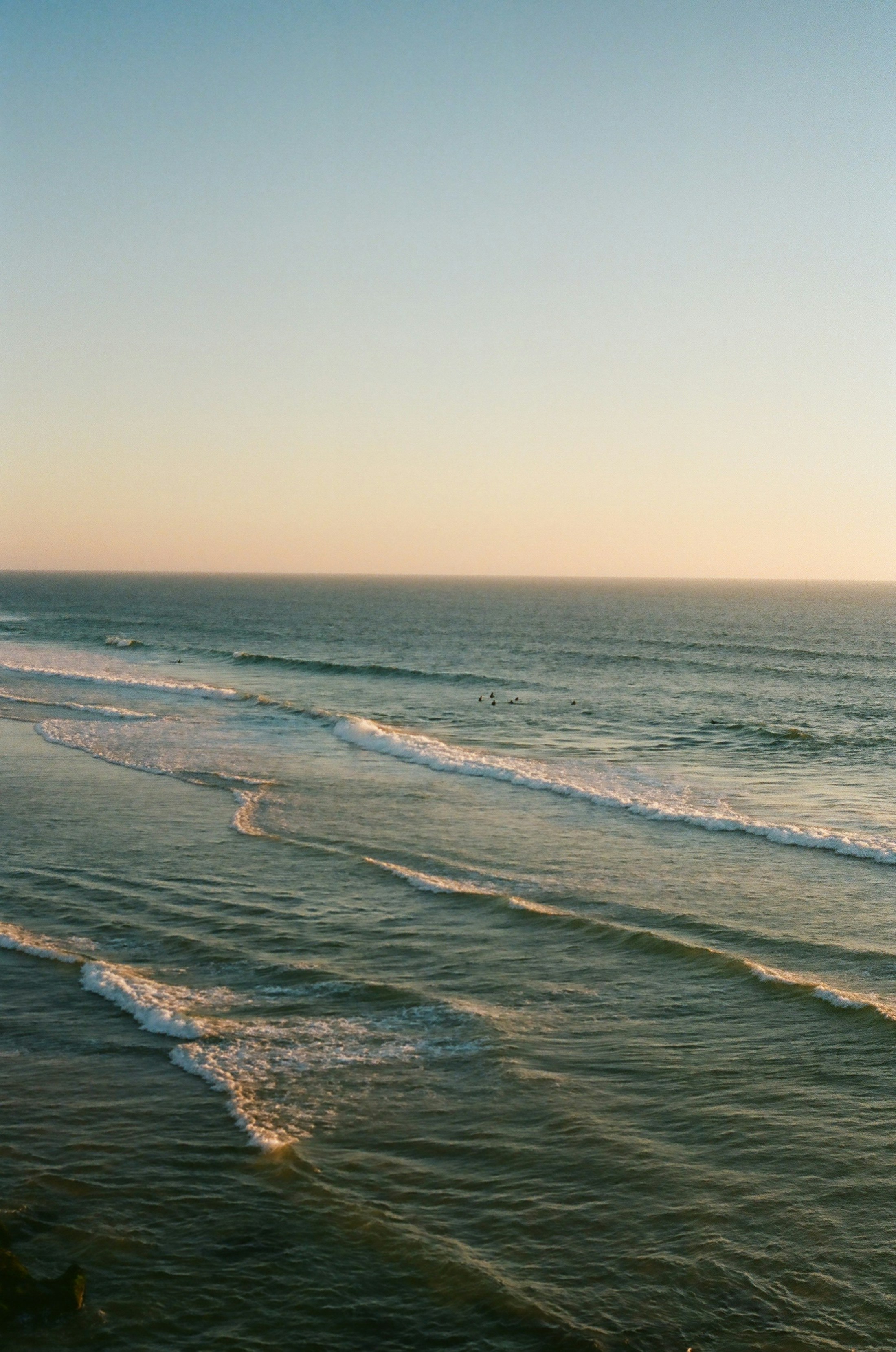 Muted ocean waves approaching a pale shoreline